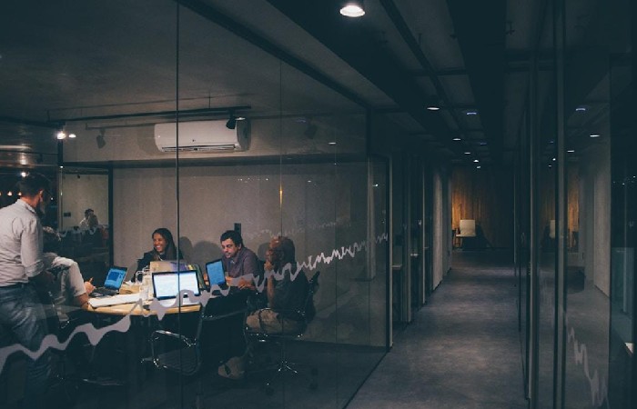 A group of professionals collaborating at a table, each using laptops, discussing proposal automation and CRM integration.

